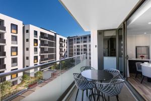 uma varanda com uma mesa, cadeiras e edifícios em Meriton Suites Coward Street, Mascot em Sydney