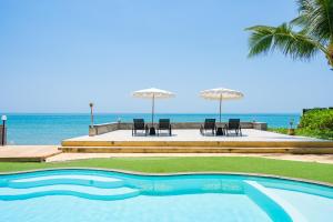 a swimming pool with chairs and umbrellas next to the ocean at 4U Resort Samui in Lamai