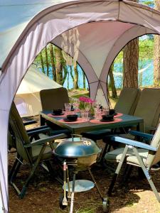 a table and chairs in a tent with a grill at Caravana Juliana - Glamping in Swaderki