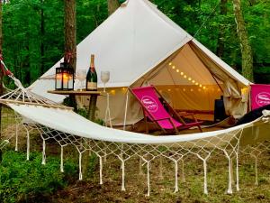 Swaderki的住宿－Caravana Juliana - Glamping，帐篷配有吊床和带葡萄酒瓶的桌子