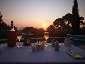 a table with wine glasses and food on it with the sunset at Maison d'Hôtes Hameau de Taur in Villefranche-dʼAlbigeois