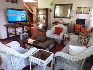 a living room with white wicker chairs and a tv at Casa Joaquin BnB in Manila
