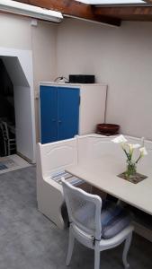 une table blanche et une chaise avec un vase de fleurs dans l'établissement La p'tite maison de la plage, à Fermanville