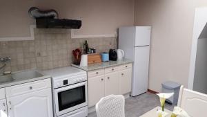 uma cozinha com electrodomésticos brancos e um frigorífico branco em La p'tite maison de la plage em Fermanville