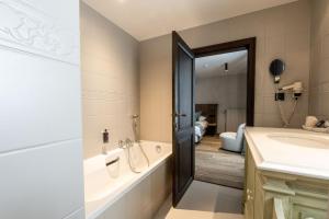 a bathroom with a tub and a sink and a mirror at Hotel LEA - Maison Caerdinael in Durbuy