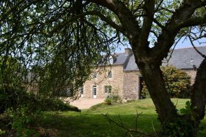 an old stone house with a tree in the foreground at La métairie du rumain in Hengoat