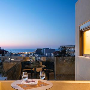 2 bicchieri da vino seduti su un tavolo sul balcone di SII City Luxury Suites a Rethymno