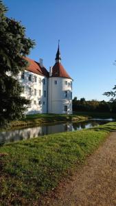 a white castle with a red roof next to a river at Ferienwohnung Windmühlenberg in Fürstlich Drehna