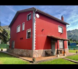 una casa roja con un banco delante en Casa La Granda en Cangas de Onís