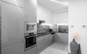 kuchnia z białymi szafkami i mikrofalówką w obiekcie Avand Apartments Debrecen w Debreczynie