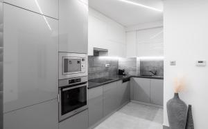 Avand Apartments Debrecen في ديبريتْسين: مطبخ مع دواليب بيضاء وميكرويف