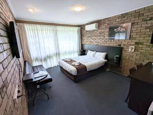1 dormitorio con 1 cama y escritorio en una habitación en Homestead Motor Inn & Apartments, en Bendigo