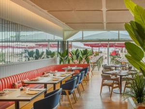 a restaurant with tables and chairs and plants at Falkensteiner Residences Jesolo in Lido di Jesolo