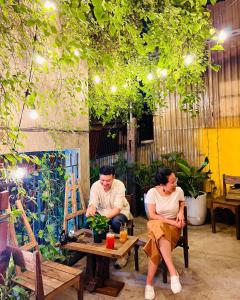 two people sitting at a table in a garden at Chủ Nhật Cafe & Homestay - 12 ngõ 41 Đường Láng - Cơ sở 1 in Hanoi