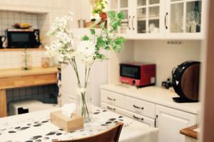 eine Vase mit Blumen auf dem Tisch in der Küche in der Unterkunft L'AtelieR Guest House Yonago in Yonago