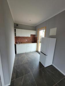 a kitchen with a white refrigerator and a tile floor at Apartamenty Drewniaki in Rydzewo