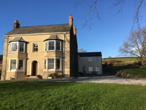 a house on the hill with a green lawn at North Down Farm in Pembroke