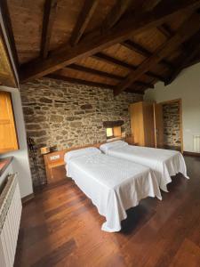 two beds in a room with a stone wall at Rectoral De Lestedo in Palas de Rei