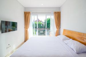 a bedroom with a white bed and a window at Dharma Guest House Seminyak RedPartner in Seminyak