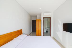 1 Schlafzimmer mit einem weißen Bett und einem Badezimmer in der Unterkunft Dharma Guest House Seminyak RedPartner in Seminyak