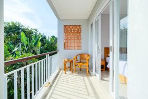 a room with a balcony with a chair and a table at Dharma Guest House Seminyak RedPartner in Seminyak
