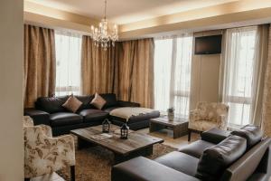 a living room with a black leather couch and chairs at Artemis Hotel Swakopmund in Swakopmund