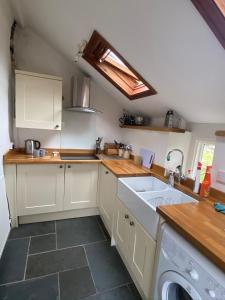 a kitchen with a sink and a washing machine at Traditional 18th Century Welsh Cottage in Llandovery