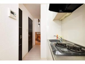 une cuisine avec cuisinière et évier ainsi qu'un couloir dans l'établissement BIANCOLINA - Vacation STAY 87604, à Fukuoka