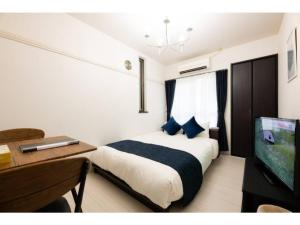 Dormitorio con cama, escritorio y TV en BIANCOLINA - Vacation STAY 87604, en Fukuoka