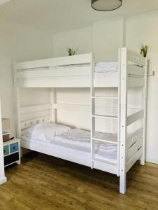 two white bunk beds in a room with wooden floors at Ferienwohnung 4 "Gut Tossens" in Butjadingen OT Tossens