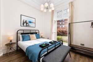 een slaapkamer met een bed en een groot raam bij 3 Bedroom Garden Apartment Opposite the Beach in Brighton & Hove