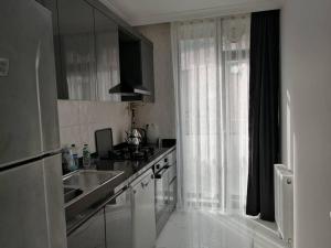eine weiße Küche mit einem Waschbecken und einem Fenster in der Unterkunft Şişli Apartment, 2 bedrooms, 250 m metro, New Modern Residence in Istanbul
