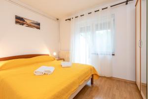 een slaapkamer met een geel bed en handdoeken bij Justic in Krk