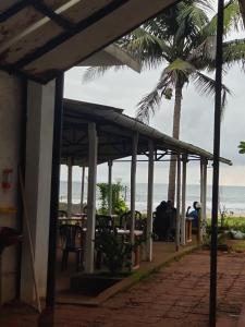 - une vue sur la plage depuis un restaurant avec un palmier dans l'établissement Mermaid Beach Resorts Vengurla, à Vengurla