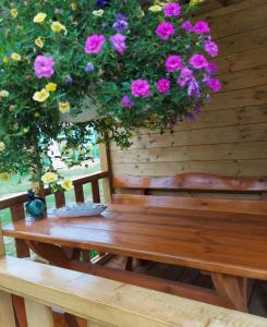 a wooden bench with flowers hanging from a wooden wall at Na polance in Chłopy