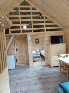 a large room with a wooden ceiling with a tv at Na polance dwa domki in Chłopy