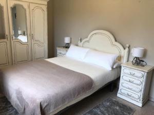 una camera da letto con un letto bianco con due comodini e due lampade di Acogedora casa próxima a la playa de Meirás. a Valdoviño