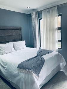 Un dormitorio con una cama blanca con una manta. en President Guest Lodge, en Louis Trichardt