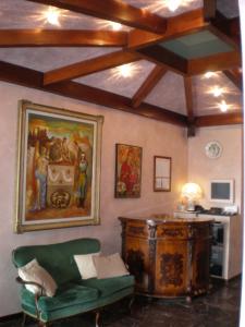 ein Wohnzimmer mit einer grünen Couch und einem Gemälde an der Wand in der Unterkunft Hotel Marcellino in Selvino