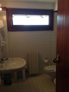 ein Bad mit einem Waschbecken, einem WC und einem Fenster in der Unterkunft Hotel Marcellino in Selvino