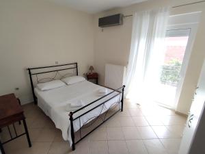 1 dormitorio con cama blanca y ventana en Philoxenia Apartments II, en Plataria