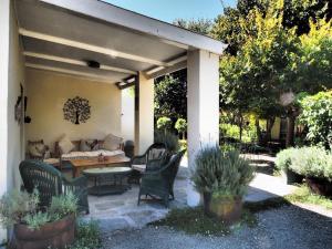 eine Terrasse mit einem Sofa, einem Tisch und Stühlen in der Unterkunft Cypress Cottage in Graaff-Reinet