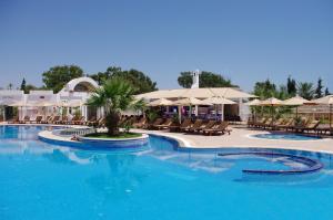 - une grande piscine avec des chaises et des parasols dans un complexe dans l'établissement Royal Nozha, à Hammamet