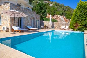 a swimming pool with an umbrella and a house at Epidavros Land Villa Orfeas in Ancient Epidauros