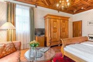 a bedroom with a bed and a couch and a table at Hotel Eisenhut in Rothenburg ob der Tauber