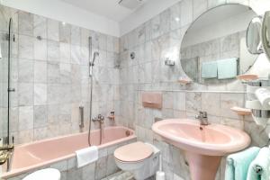 a bathroom with a pink tub and a sink and a toilet at Hotel Eisenhut in Rothenburg ob der Tauber +37 photos