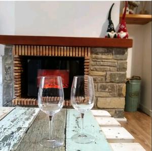 two wine glasses sitting on a table in front of a fireplace at CHECK-IN CASAS La casa de Teresa in Benasque