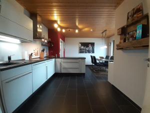 a large kitchen with white cabinets and a dining room at Ferienwohnung 75m² Terrasse Parkplatz WallBox Nürburgring in Herresbach