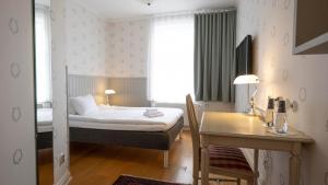 Schlafzimmer mit einem Bett, einem Tisch und einem Schreibtisch in der Unterkunft Lundsbrunn Resort & Spa in Lundsbrunn
