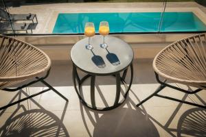 een witte tafel met twee glazen en twee stoelen bij Solis Ortus Villa! in Zakynthos